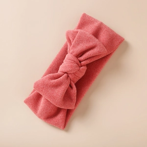Détail du bandeau bébé extensible avec un grand nœud en tricot de couleur corail