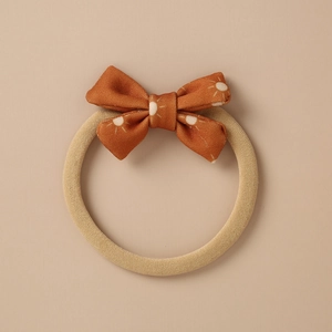 Close-up of rust orange bow hair band with white sun patterns and knitted texture
