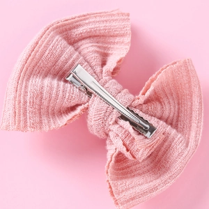 Detail der rosa gestrickten Haarschleife mit silberner Klemme und feiner Rippenstruktur