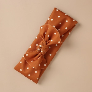 Detailed view of caramel knit baby headband with white polka dots and large handmade bow