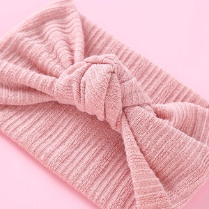 Nahaufnahme von rosa gestricktem Baby-Stirnband mit stilvollem Knoten auf farbigem Grund