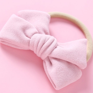 Gros plan d'un bandeau pour bébé avec nœud en velours rose et bande en nylon souple