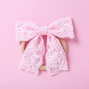 Gros plan détaillé du bandeau à nœud en dentelle rose brodée pour bébés filles