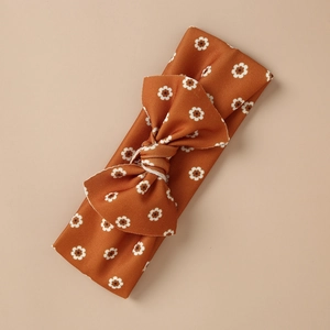 Vintage caramel elastic headband for infants featuring white daisy prints and a bow