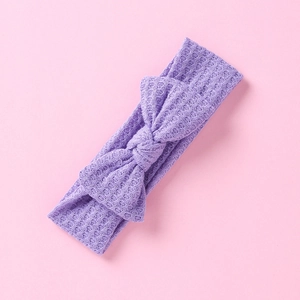 Détail d'un bandeau bébé en maille gaufrée violette avec un grand nœud sur rose