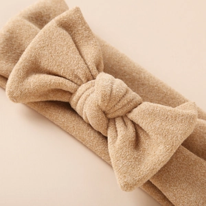 Gros plan du bandeau bébé en imitation cachemire camel avec noeud tricoté