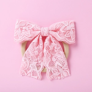 Vue détaillée du bandeau pour bébé avec nœud en dentelle rose et motifs floraux élégants