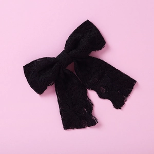 Detailansicht der schwarzen Spitzen-Haarschleife mit Bändern auf rosa Hintergrund