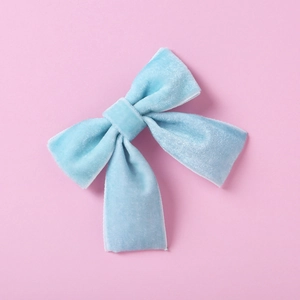 Gros plan d'un nœud papillon en velours bleu clair pour bébés sur fond rose
