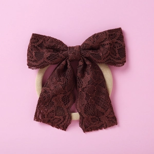 Vue détaillée du bandeau en dentelle bordeaux avec nœud papillon et élastique crème