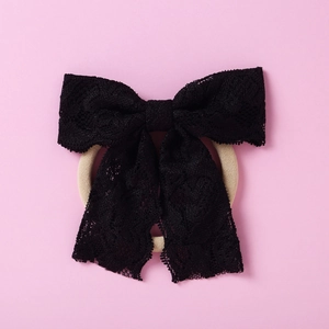 Détail d'un bandeau en dentelle noire avec nœud papillon et bande élastique de couleur beige