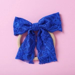 Détail d'un nœud en dentelle bleu marine et bandeau en nylon souple pour bébés filles