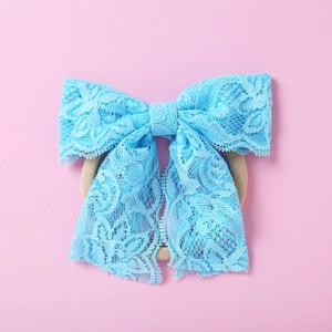 Détail d'un bandeau en dentelle bleu vif avec nśud floral pour bébés et petites filles