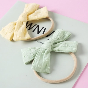 Detail von gelben und minzgrünen gepunkteten Schleifen auf weichen Nylon-Baby-Stirnbändern