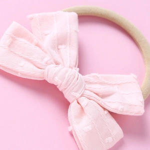 Makroaufnahme einer rosa Baumwollschleife mit feiner Punkte-Jacquard-Textur für Babys