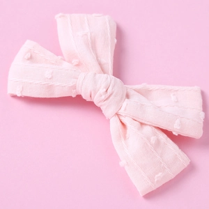 Detail of baby hair clip featuring pink jacquard cotton fabric with textured dots and stripes