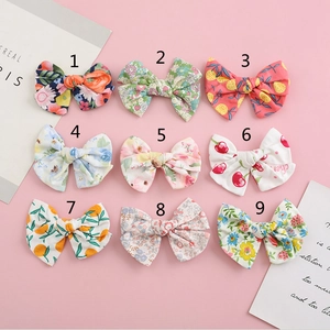 Close-up of nine cotton bow hair clips featuring floral and fruit patterns for kids