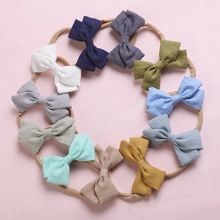 Vue à plat de 10 bandeaux en nylon à nœud gaufré coloré pour bébés sur fond rose