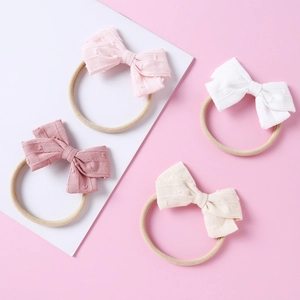 Detailed view of four soft jacquard bow headbands in pink, white, and beige tones
