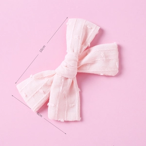 Detail view of pink cotton bow hair clip with textured jacquard dots and stripes