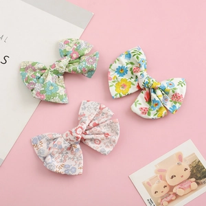 Three-piece floral cotton bow hair clips set for toddlers on a pink decorative background