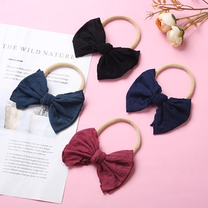 Bandeaux bébé en nylon colorés avec grands nœuds en tissu disposés sur un fond rose