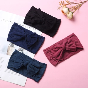 Detailed flat lay of soft nylon baby headbands with large bows in four classic colors