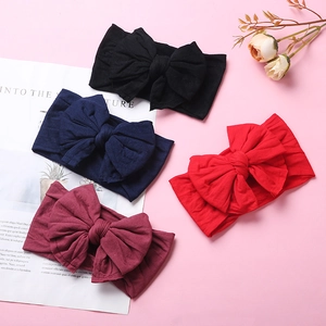 Detailed view of four soft nylon baby headbands with large bows in multiple colors