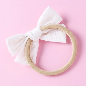 Gros plan d'un bandeau pour bébé avec un nœud en dentelle blanche et motif à carreaux