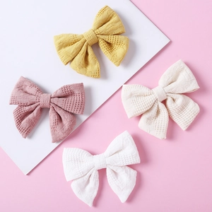 Nahaufnahme von vier Jacquard-Baumwollschleifen in Gelb, Rosa, Beige und Weiß für Mädchen
