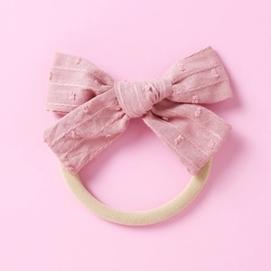 Detail eines rosa Stoffschleifen-Stirnbands mit Polka-Dot-Struktur und Gummiband
