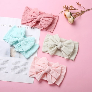 Detail view of four soft nylon baby headbands with large double bows in assorted pastel colors