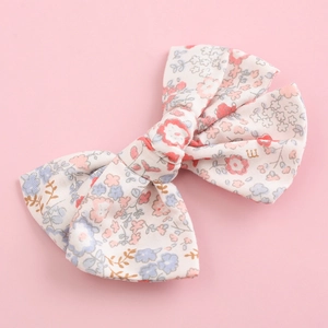 Detail of floral cotton bow hair clip with pink and blue patterns on a pastel background