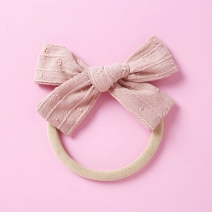 Detail eines weichen Nylon-Babystirnbands mit rosa gepunkteter Schleife auf rosa Grund