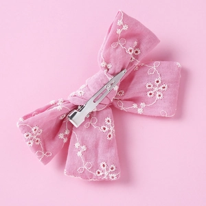 Detail of pink embroidered lace bow hair clip with white flowers and silver metal alligator clip