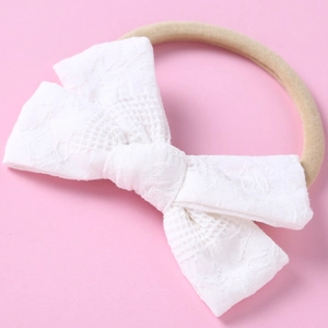 Détail de bandeau en dentelle blanche avec nœud et ruban en nylon pour bébé fille
