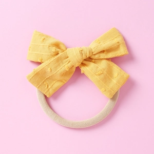 Detail eines gelben gepunkteten Baby-Haarbandes mit elastischem Nylon-Band und Schleife