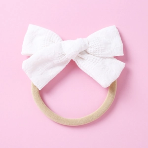 Détail du nœud en dentelle blanche sur bandeau élastique en nylon pour bébé en rose