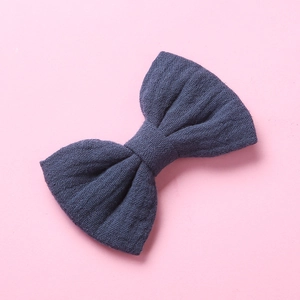 Dettaglio del fermaglio per capelli con fiocco in cotone blu scuro e trama intrecciata su rosa