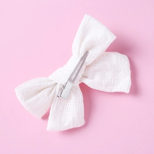Close-up of white lace bow hair clip with intricate patterns and silver metal duckbill clip