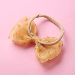 Gros plan du grand nœud en tulle orange sur un bandeau souple en nylon pour bébé