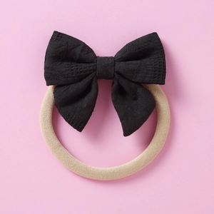 Détail du bandeau avec nœud en dentelle noire et ruban élastique beige pour bébé