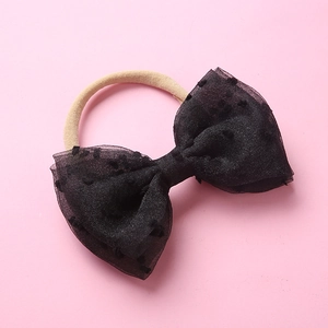 Détail du bandeau bébé avec nœud en tulle à pois noirs sur bande élastique douce
