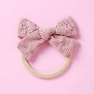 Détail d'un bandeau bébé avec nœud rose poudré en tissu à carreaux et élastique souple