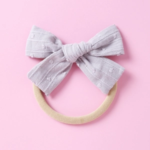 Detailierte Textur der fliederfarbenen gepunkteten Schleife und Nylon-Stirnband für Babys