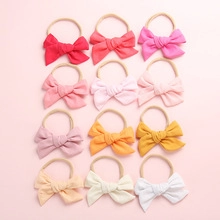 Lot de 12 bandeaux pour bébé avec nœuds gaufrés en couleurs assorties sur fond rose doux