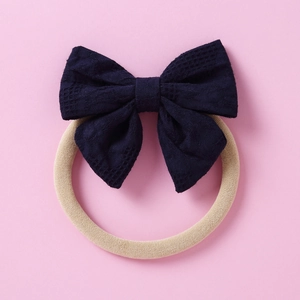 Détail du nœud en coton bleu foncé sur un bandeau bébé en nylon souple à texture quadrillée