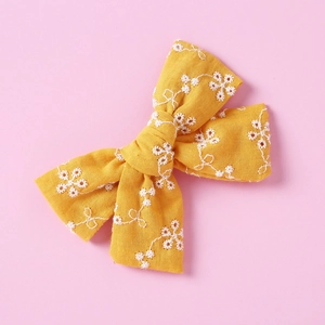 Macro view of handmade yellow cotton lace bow with white floral embroidery and wavy textures
