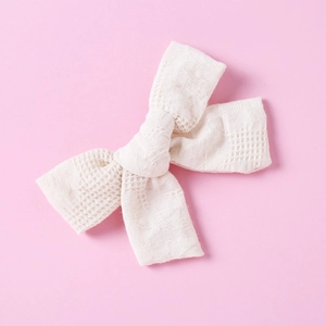 Detail of a handmade cream white cotton bow hair clip with fine grid texture for girls