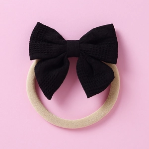 Détail du bandeau bébé avec nœud noir à texture gaufrée sur nylon beige doux